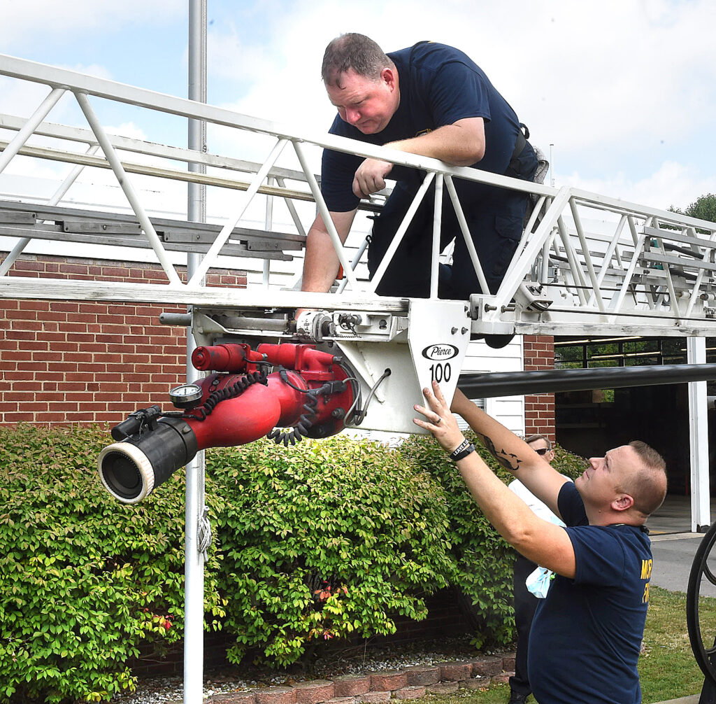 firefighters check the nozzle on extension ladder